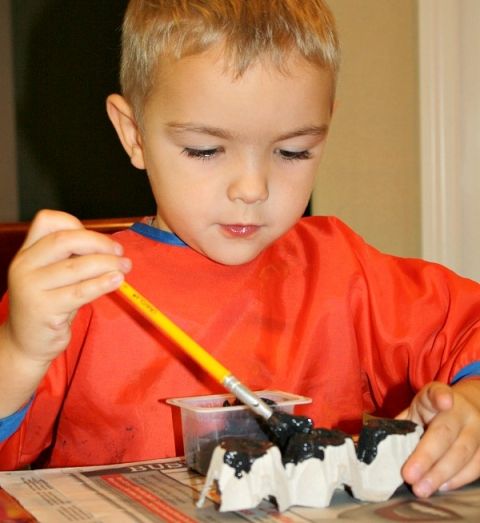 kid making egg carton bats as halloween crafts for kids